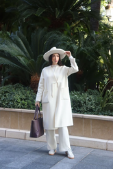 a lady in a white wool coat and a pair of white pants